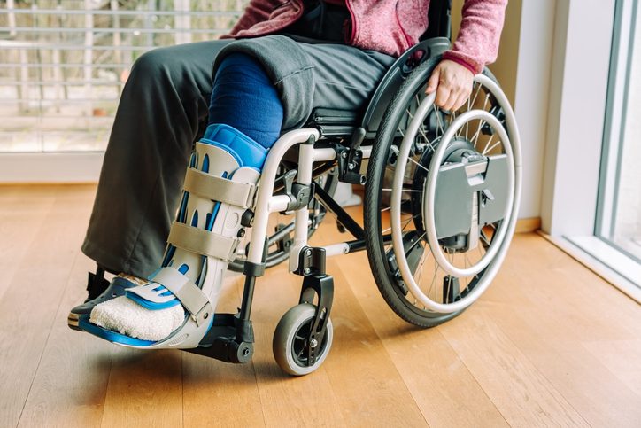 Detail or woman in a wheelchair with leg brace after sport injury